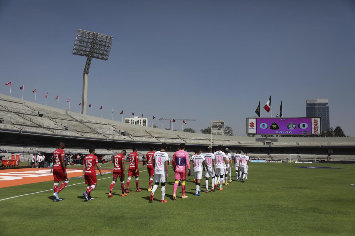 Los jugadores Toluca (izquierda) y Pumas entran a la cancha para el partido del torneo Apertura en el Estadio Olímpico.