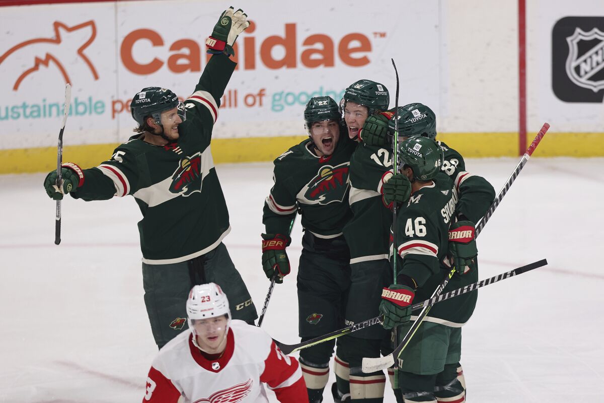 Minnesota Wild left wing Matt Boldy (12) is surrounded by teammates in celebration after scoring a goal against the Detroit Red Wings during the first period of an NHL hockey game Monday, Feb. 14, 2022, in St. Paul, Minn. (AP Photo/Stacy Bengs)