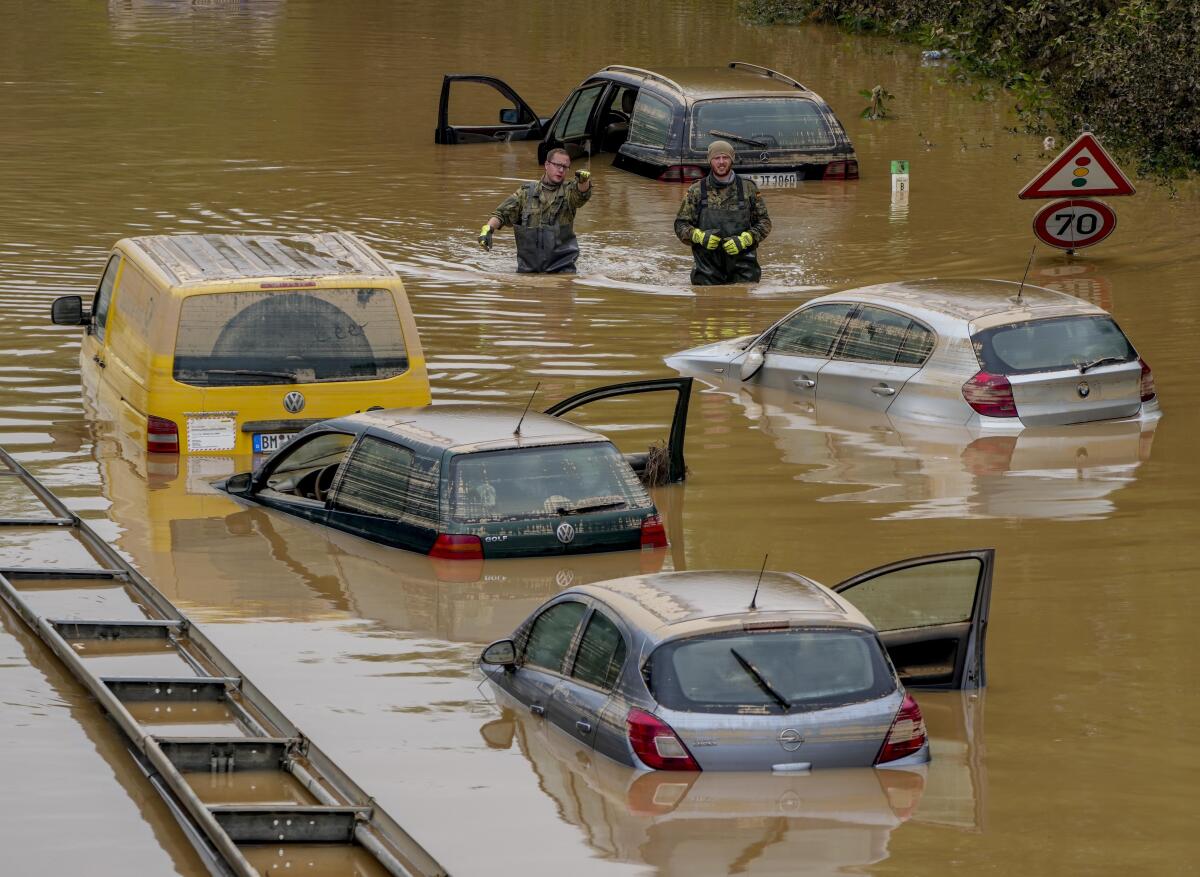 People check for victims in flooded cars on a road in Erftstadt, Germany