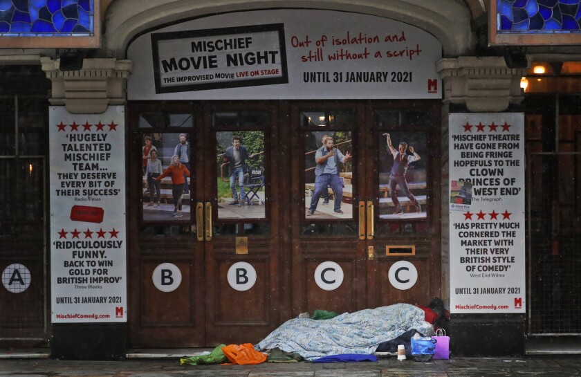 A rough sleeper rests at the entrance of theatre, closed due to the COVID-19 pandemic in London, Monday, Feb. 8, 2021. The homeless are not listed among the British government's highest priority groups for the vaccine rollout — currently people over 70 years old, care home residents, frontline health and social care workers, as well as the clinically vulnerable. Because those sleeping rough and people in refuges have no address doctors can contact them at, some local authorities across Britain have begun sending out roving vaccination teams to identify the clinically vulnerable among them so they can have access to the jab.(AP Photo/Frank Augstein)