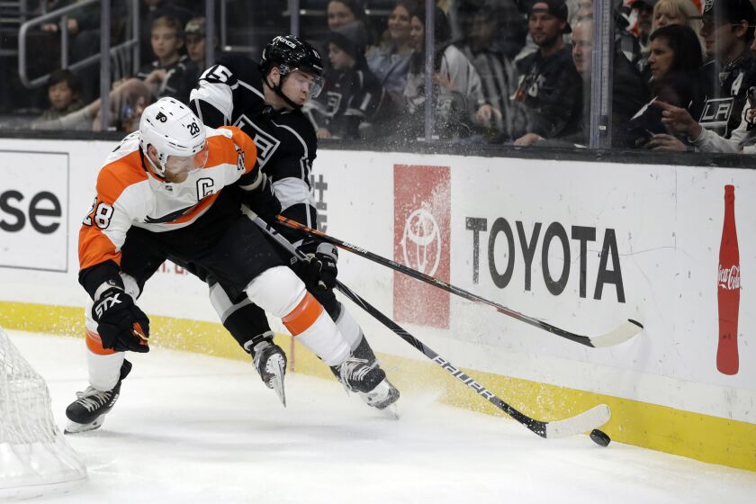Philadelphia Flyers' Claude Giroux, left, is defended by Los Angeles Kings' Ben Hutton during the first period of an NHL hockey game Tuesday, Dec. 31, 2019, in Los Angeles. (AP Photo/Marcio Jose Sanchez)