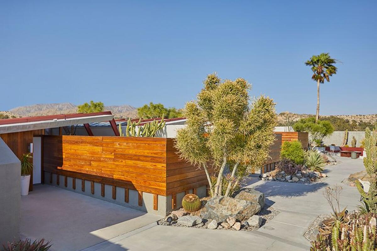 A compound made from concrete, redwood, glass and steel with desert plants around it.