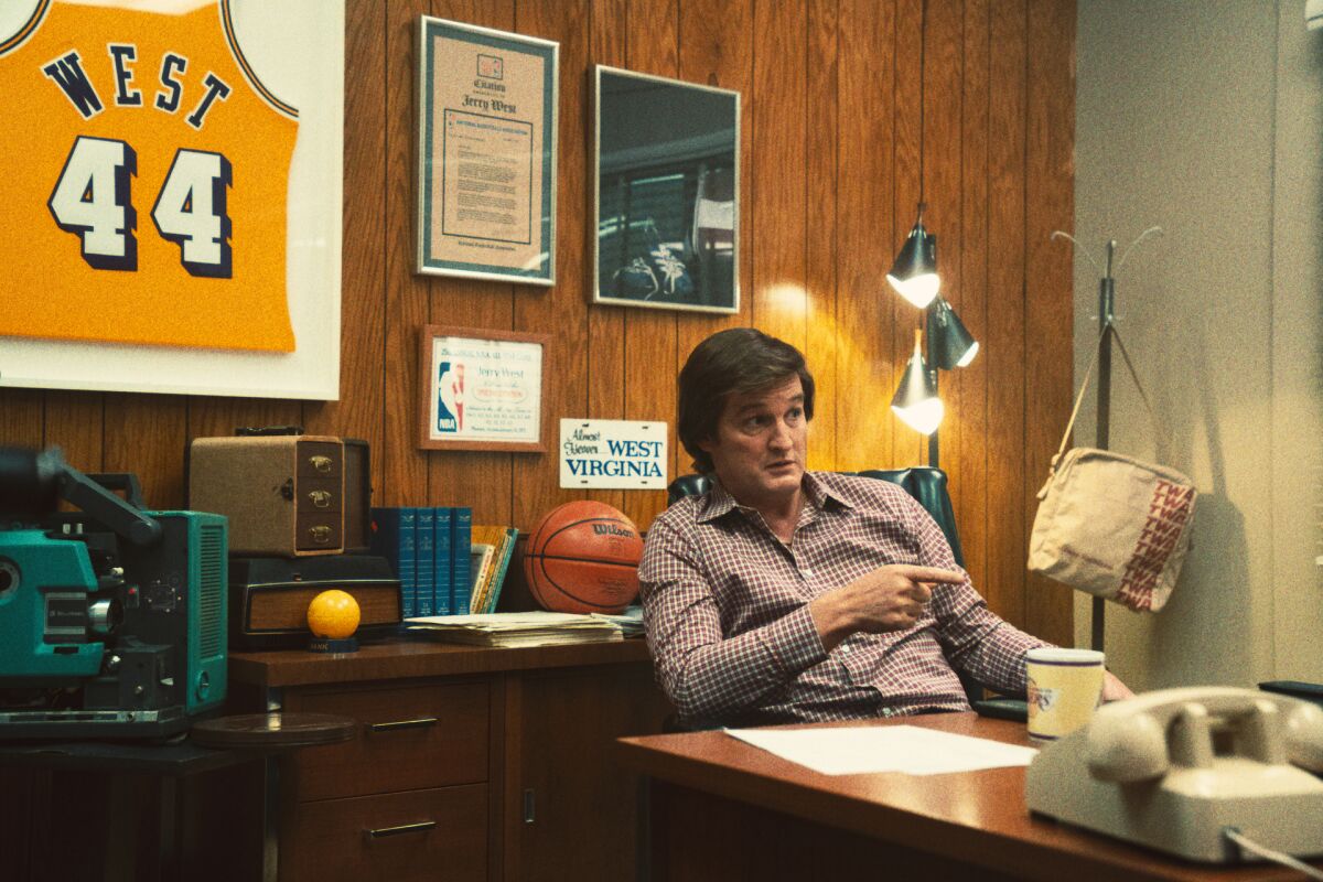 A man at his desk in an office decorated with Lakers memorabilia
