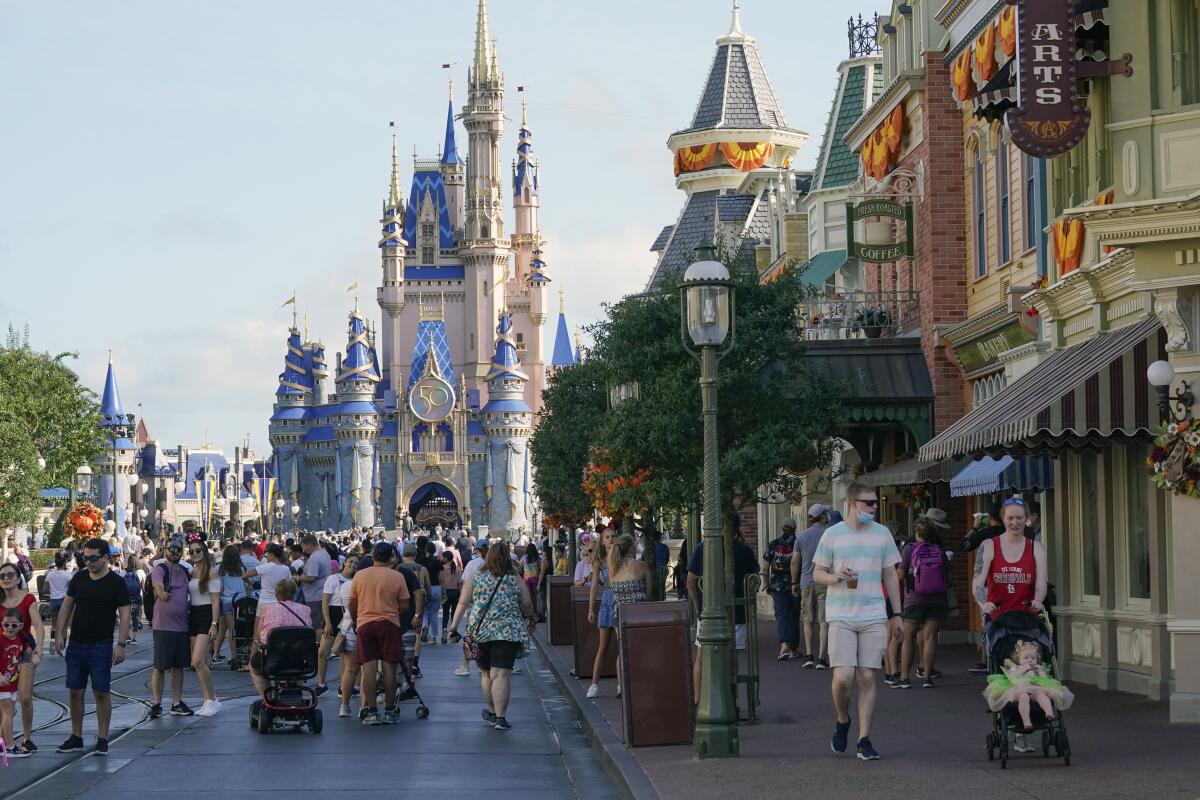 Guests stroll along Main Street at the Magic Kingdom theme park at Walt Disney World, a castle in the background.