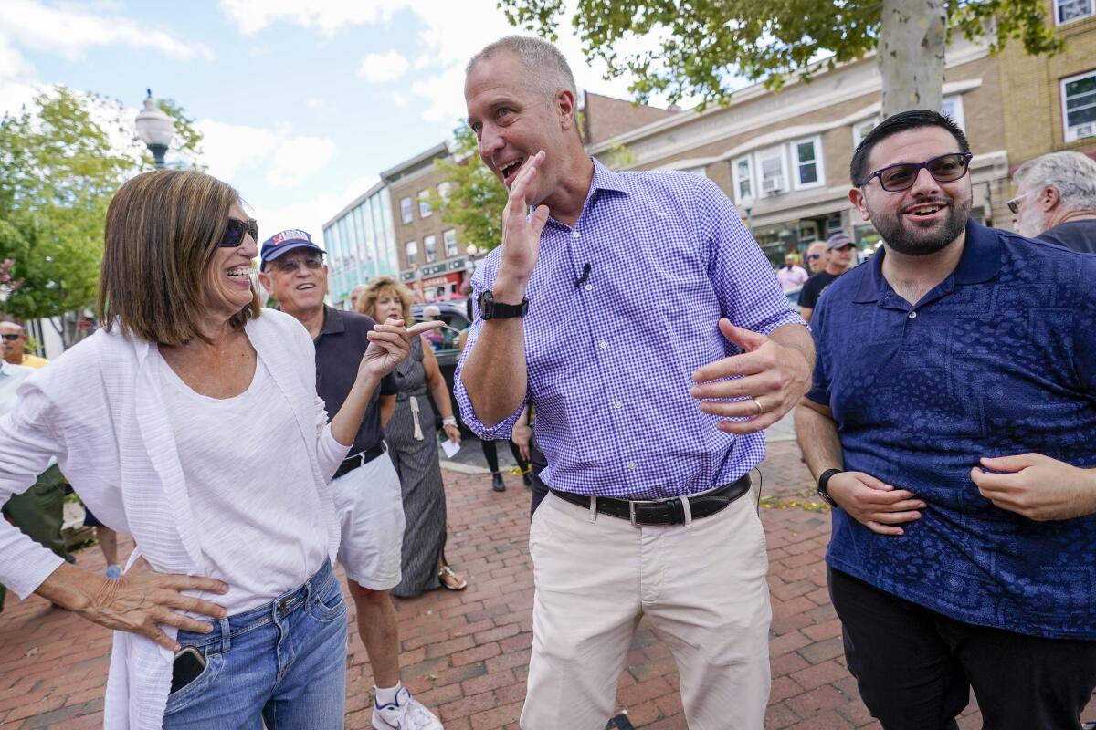 Rep. Sean Patrick Maloney smiles and talks to supporters on a a busy, brick-paved sidewalk. 