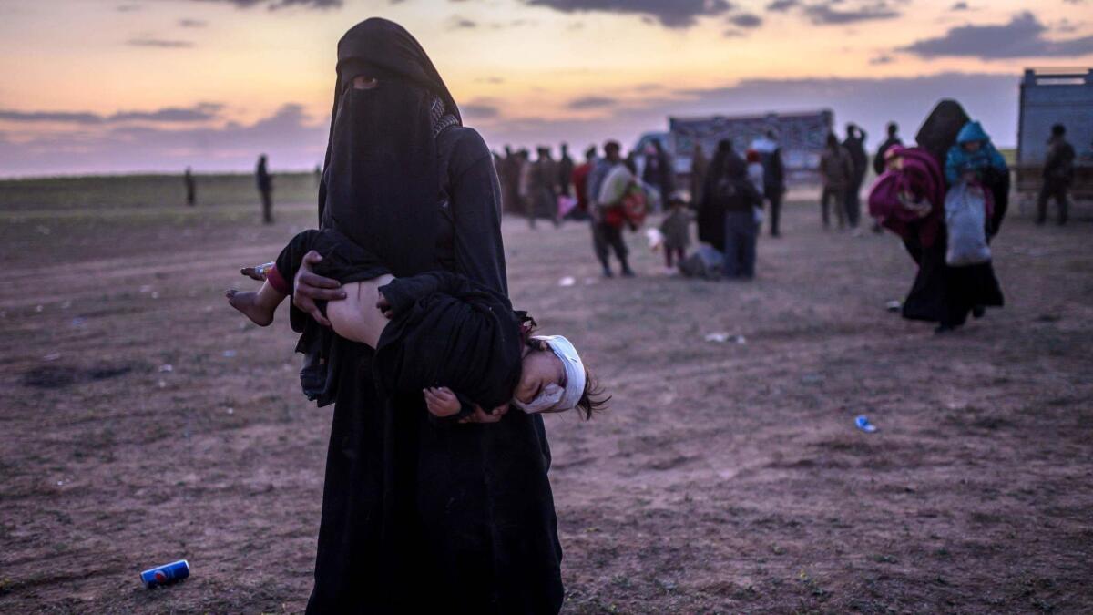 A woman carries her injured child as she walks to members of the Kurdish-led Syrian Democratic Forces from the Islamic State group's last holdout of Baghouz, in eastern Syria, on March 4, 2019.