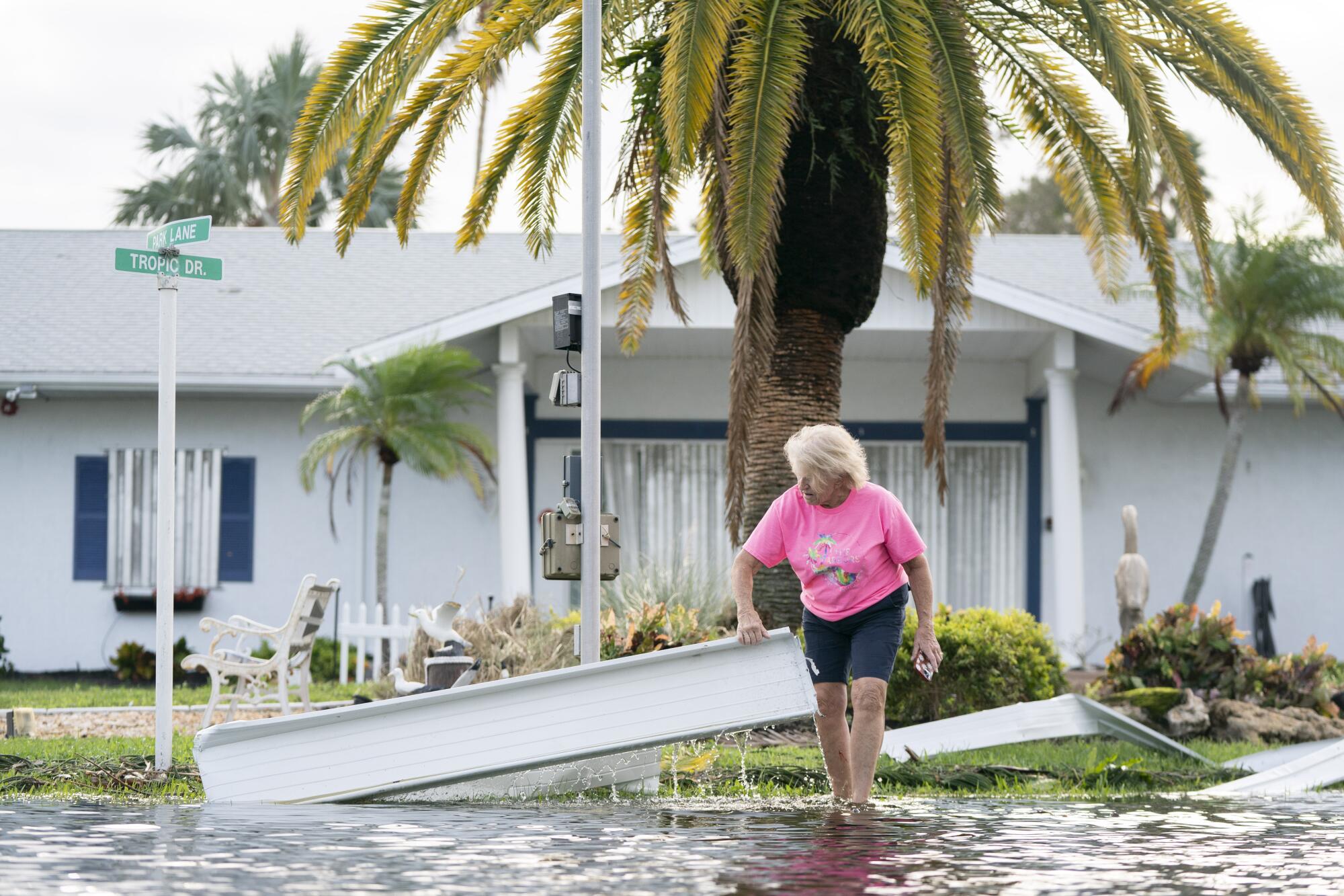 A woman moves debris on a flooded street in Osprey, Fla., in the wake of Hurricane Milton.