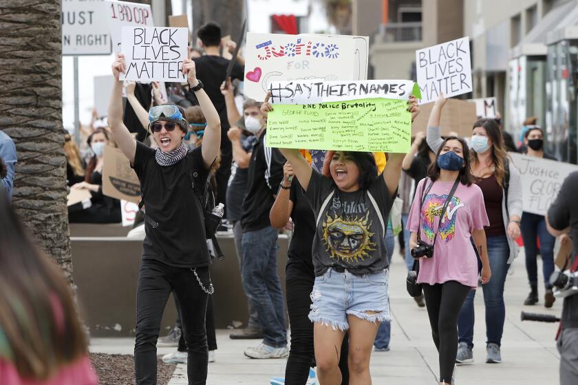Supporters for the Black Lives Matter movement shout "No justice! No peace!" as they march along Newport Boulevard during a peaceful protest against police brutality at Triangle Square on Friday in Costa Mesa.