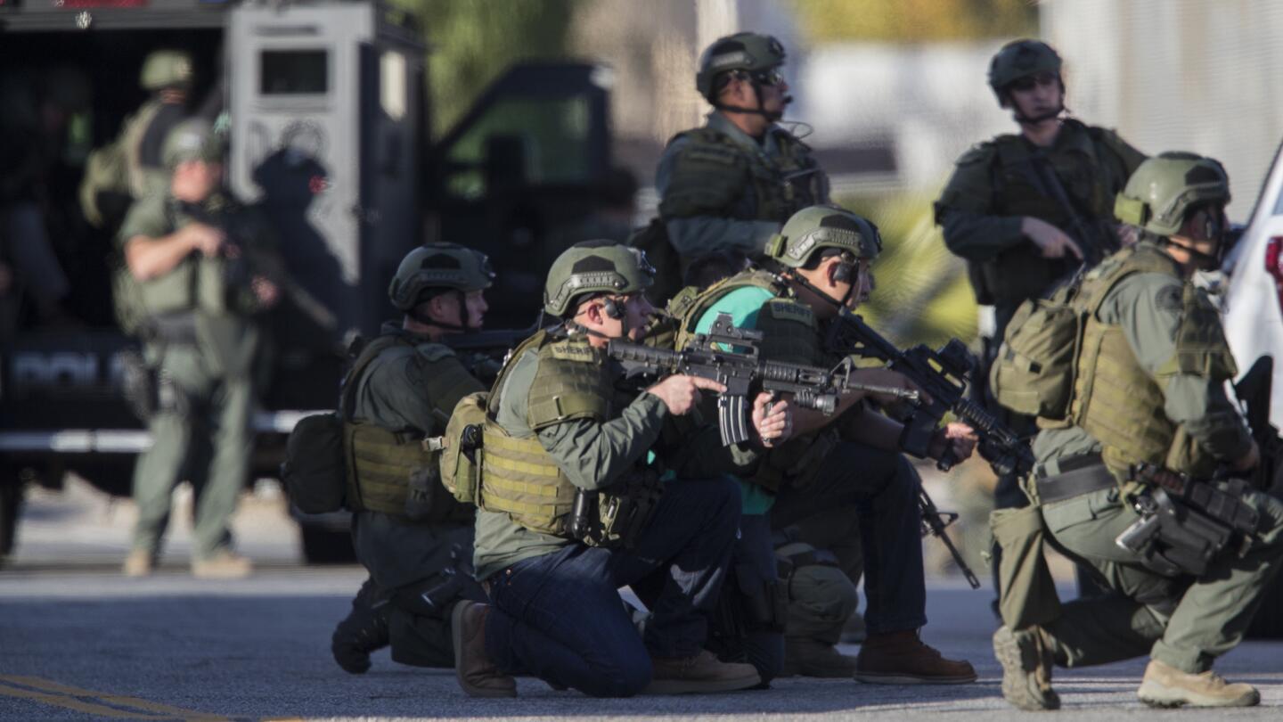 San Bernardino County Sheriff's Department SWAT officers crouch on Richardson Street searching for the shooters involved in the Inland Regional Center attack.