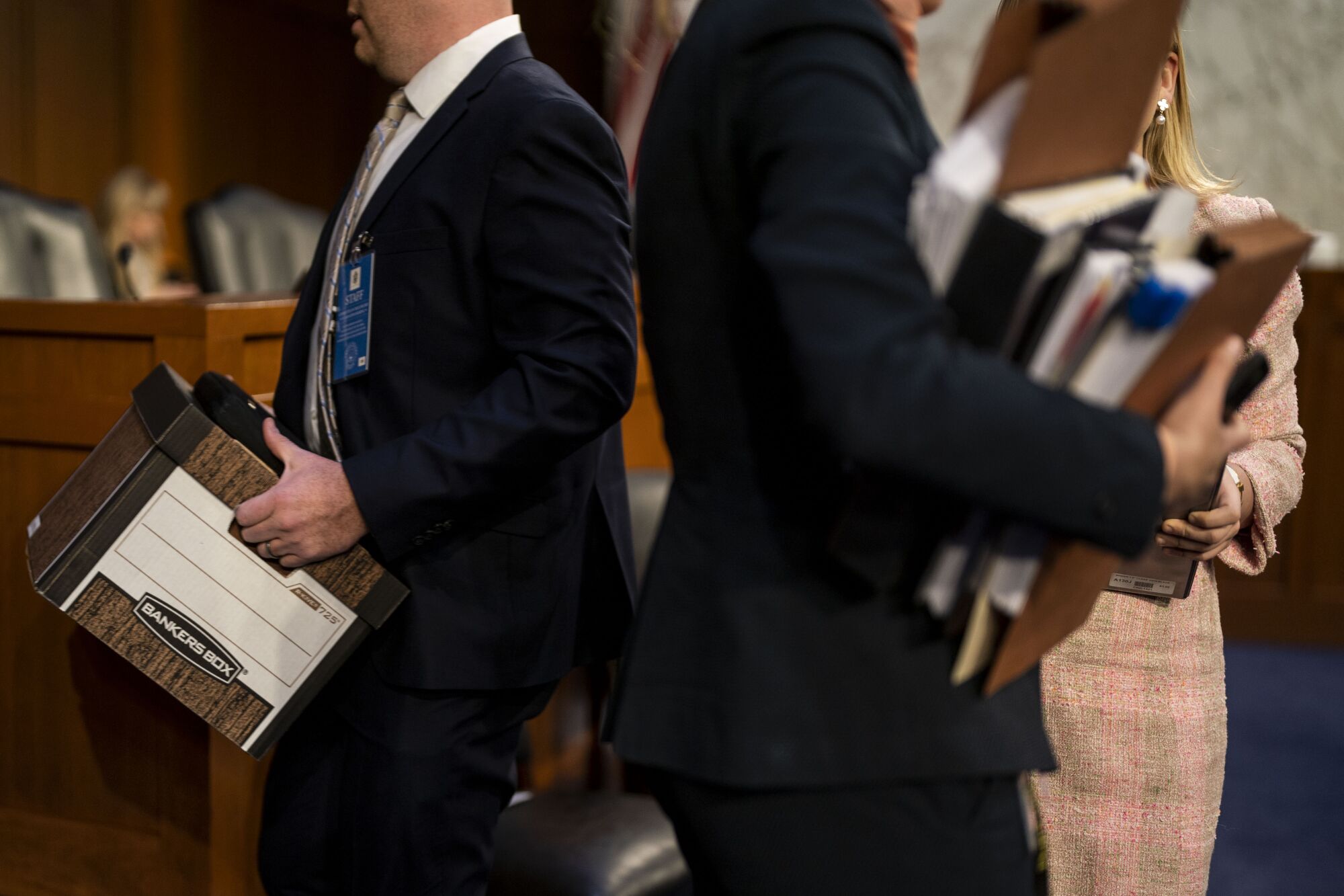 Staffers carry boxes and folders in and out of the Senate hearing room.