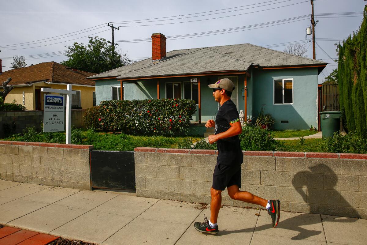 A runner runs past a home, for sale along Buena Vista Street, in March 2019 in Burbank, Calif.