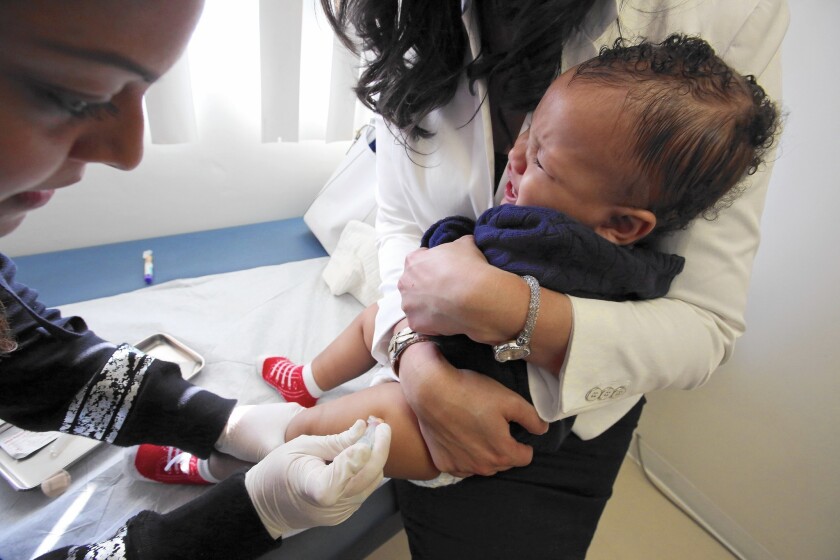 Medical assistant Daisi Minor, left, gives a measles, mumps and rubella vaccine to 1-year-old Kristian Richard while his mother, Natasha, holds him at a medical facility in Los Angeles.