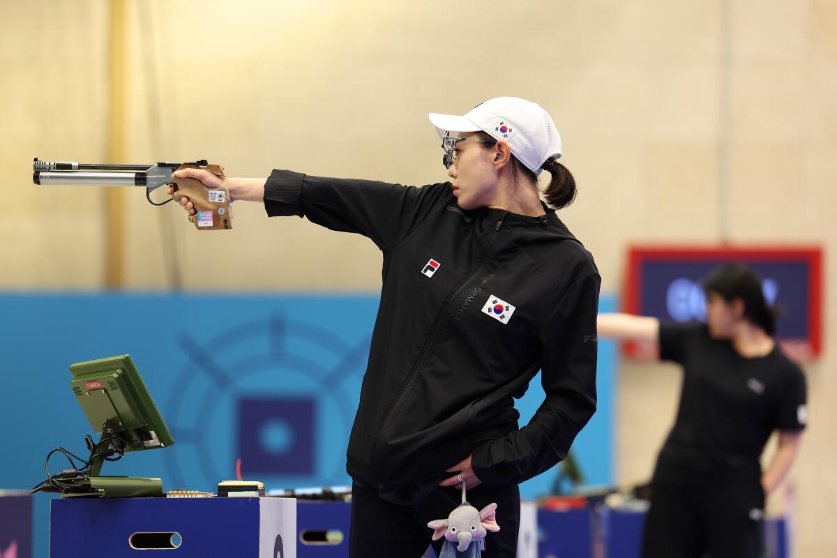 A woman points a pistol.