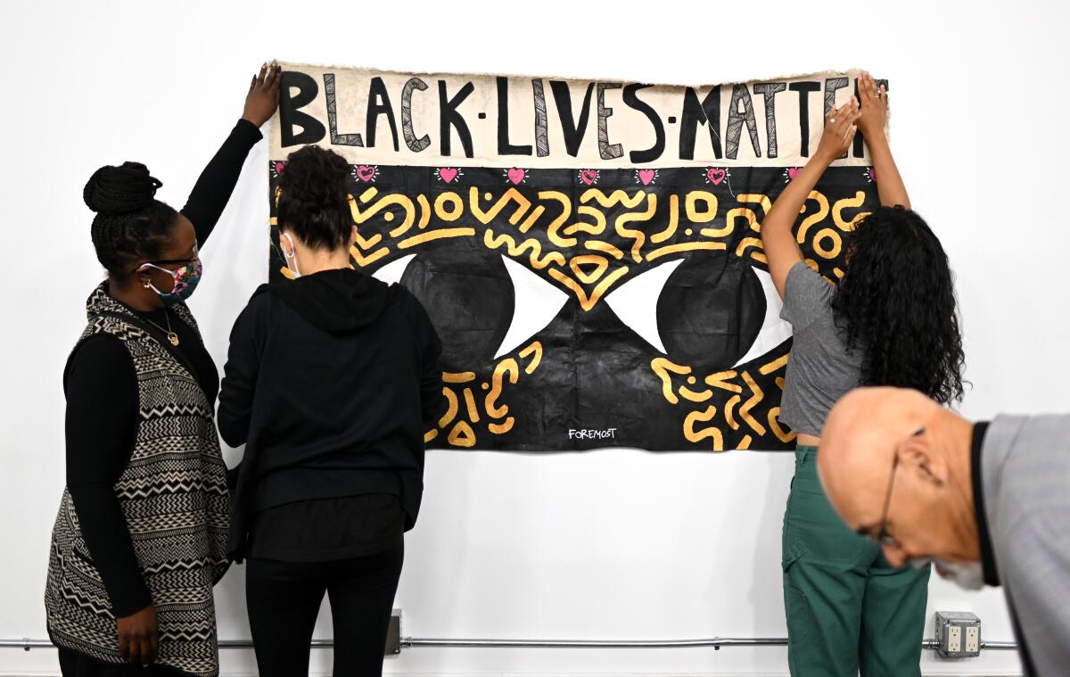 Several activists putting a panoramic Black Lives Matter poster on a wall