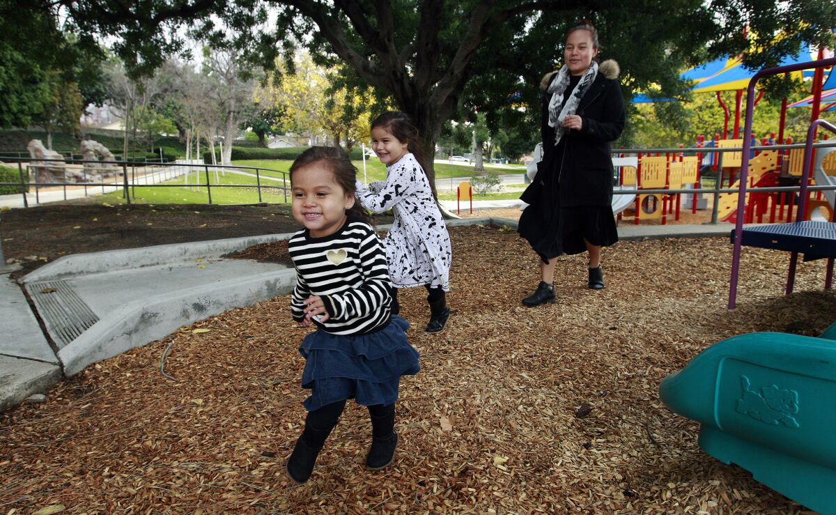 May Martinez chases after her daughters Olivia Munoz and Arabella Munoz as they play a game of hide and seek. Martinez is losing access to subsidies provided by the state to cover child care because her husband got a raise.