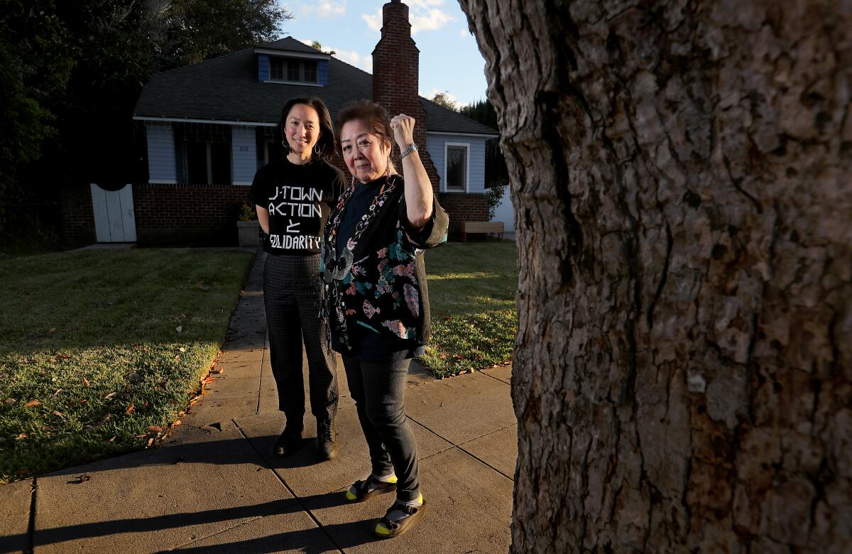 A younger woman and an older woman (with her first raised) standing outside