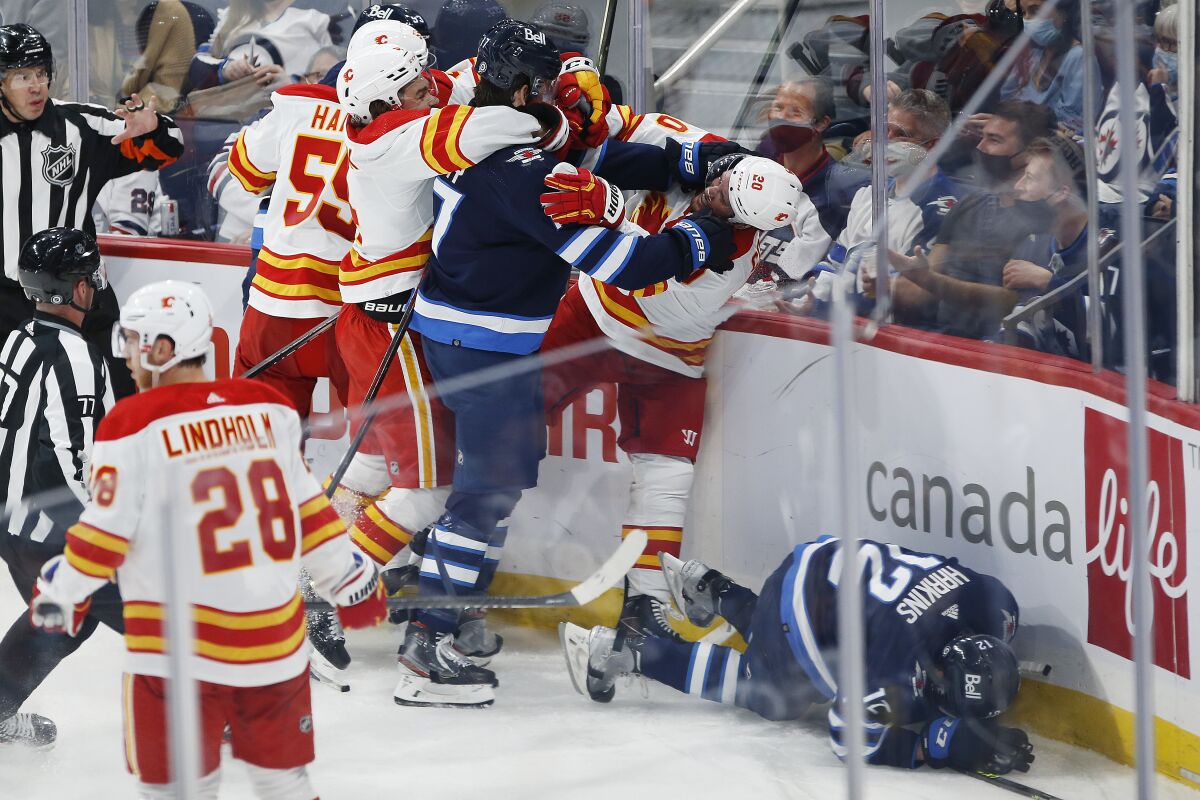 Winnipeg Jets' Adam Lowry (17) grabs Calgary Flames' Blake Coleman (20) after he boarded Jets' Jansen Harkins (12) during the second period of an NHL hockey preseason game Wednesday, Oct. 6, 2021, in Winnipeg, Manitoba. (John Woods/The Canadian Press via AP)