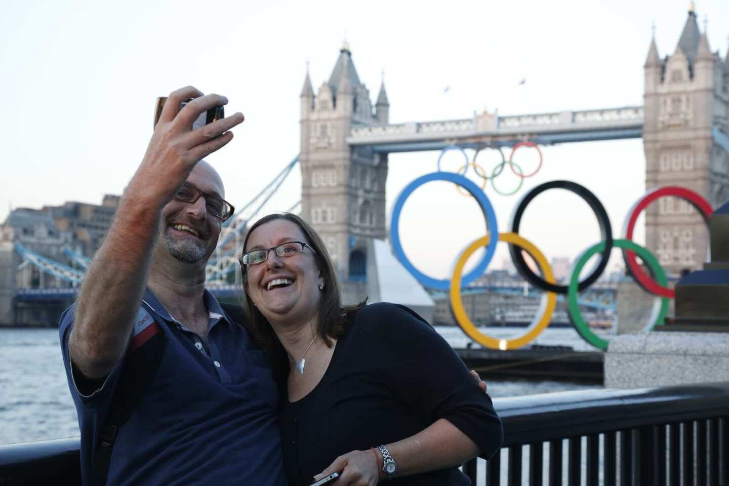 Friends Stephen Hudson and Tracey Tyer take a photo together with Tower Bridge and the Olympic rings at Battersea Park.