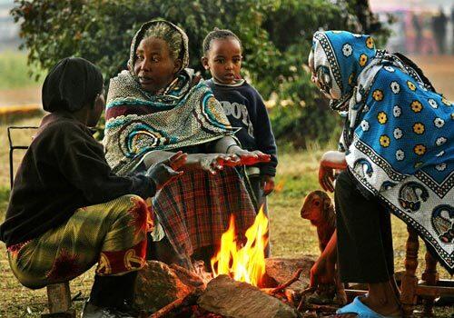 Monica Waithira, age 67, and her family warm their hands over a fire in the park in Nairobi. They have been living at the entrance to a Kenyan Air Force base since Jan. 1, when thugs attacked their home and killed all of their animals except for one young lamb. Waithira is now bottle feeding the lamb and plans to keep it as a pet. She doesn't know when she will be able to go home.