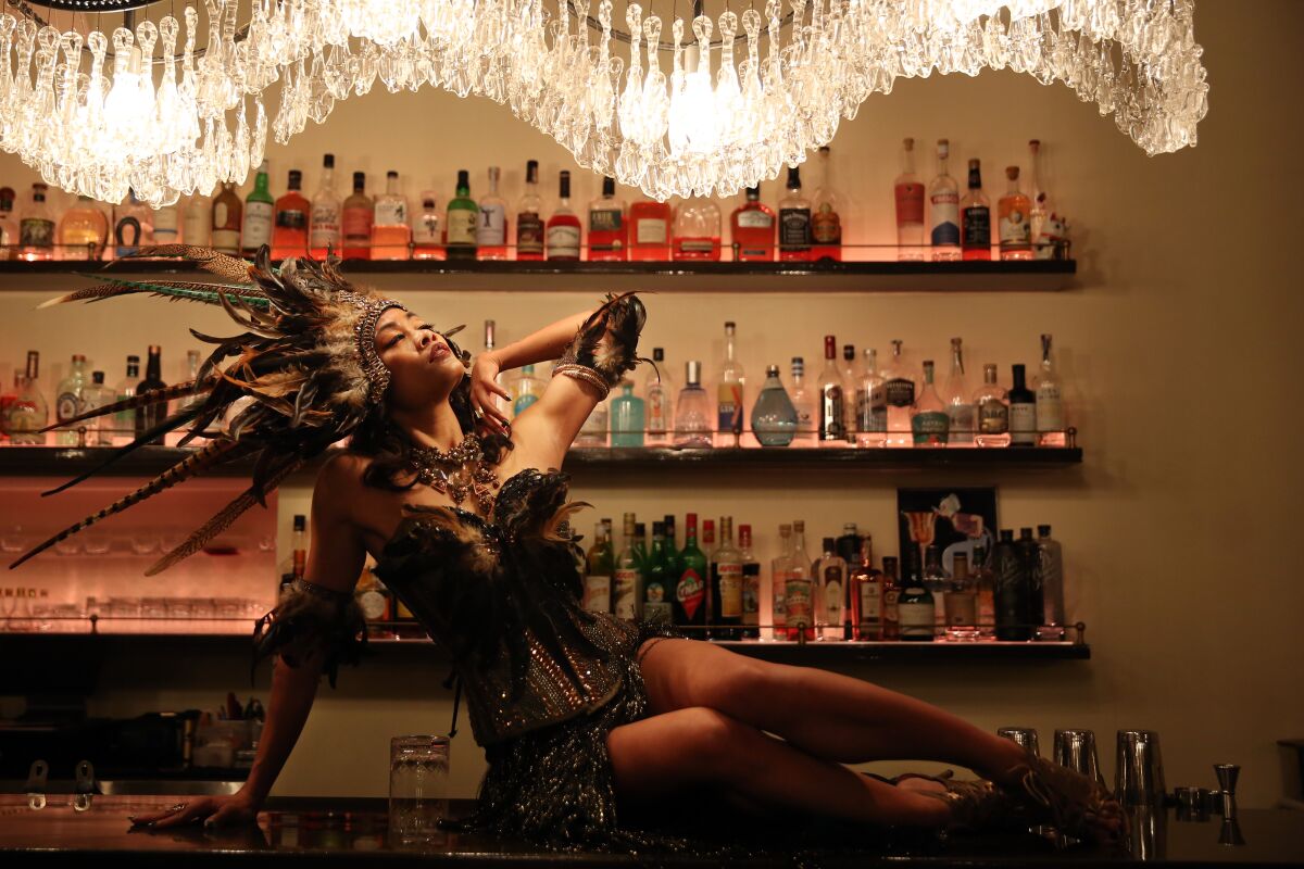 Burlesque dancer Mizon Garde leans back in front of a wall of bottles at Genever Bar in Los Angeles.