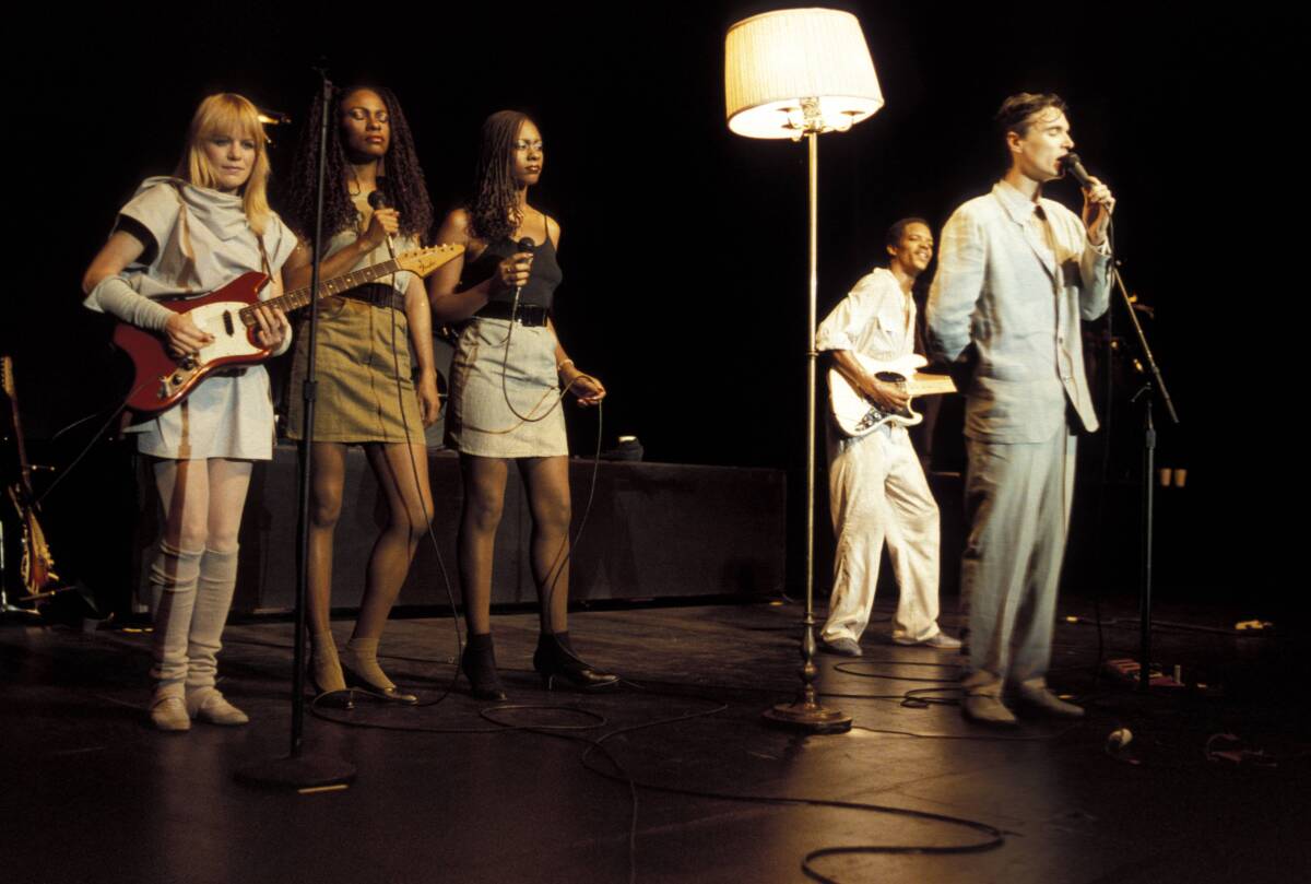 An art-rock band performs with a lamp onstage.
