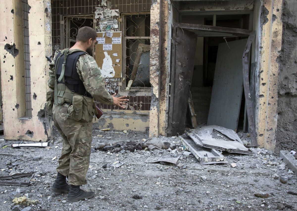 A pro-Russia fighter in Donetsk, eastern Ukraine, discovers a body near an apartment building that was heavily damaged by shelling Tuesday.