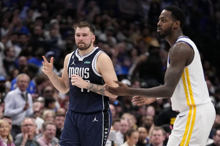 Dallas Mavericks guard Luka Doncic (77) celebrates sinking a three point basket as Golden State Warriors' JaMychal Green, right, looks on in the second half of an NBA basketball game, Wednesday, March 22, 2023, in Dallas. (AP Photo/Tony Gutierrez)