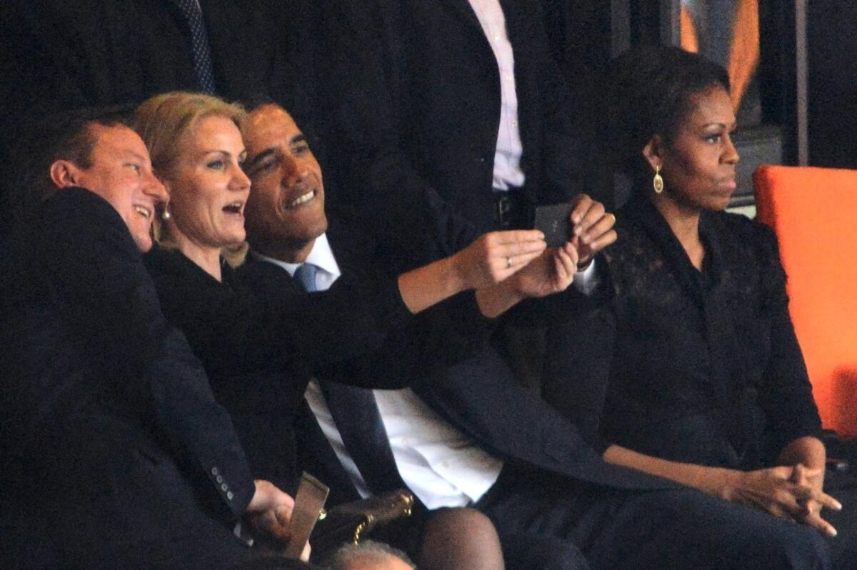 President Obama and British Prime Minister David Cameron pose for a picture with Danish Prime Minister Helle Thorning-Schmidt during the memorial service for Nelson Mandela in South Africa. First Lady Michelle Obama is next to the president.
