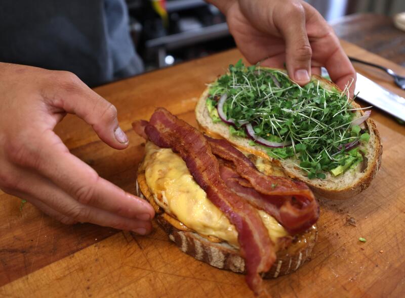 Owen Han's hands putting together the halves of his OG Spicy Chicken Sandwich.