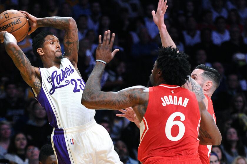 Lakers guard Lou Williams leaps to try to make a pass over Clippers center DeAndre Jordan and guard J.J. Redick.