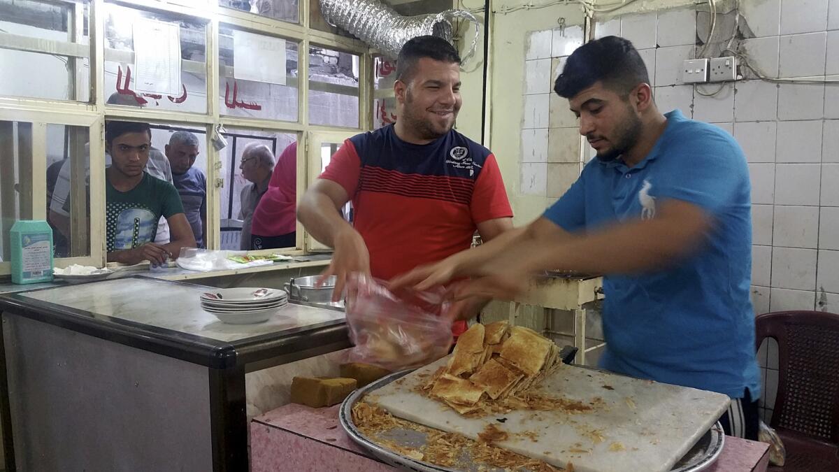 Qusai Taai, in red, prepares to serve a customer at his Kahi of Karrada cafe in Baghdad.