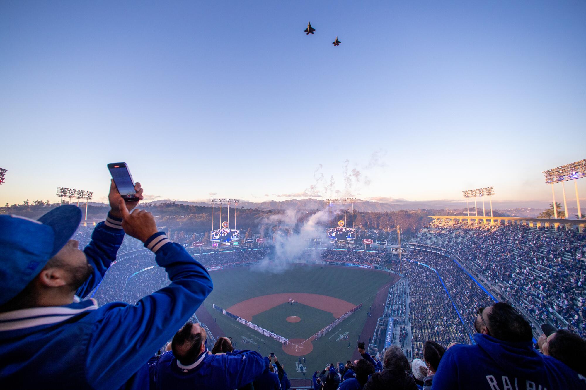 A fan takes a photo of a military flyover at Dodger Stadium before Thursday's season opener.