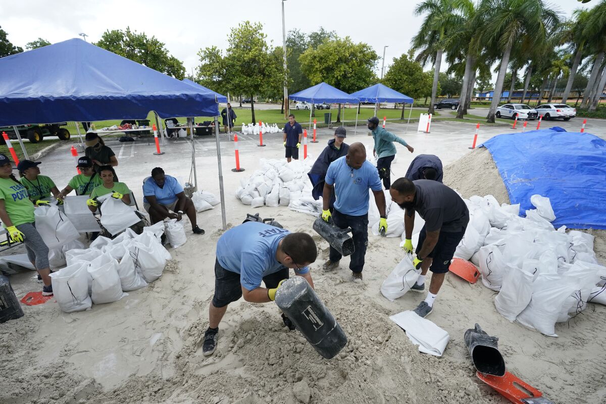 City workers fill sandbags at a drive-thru sandbag distribution event for residents ahead of the arrival of rains associated with tropical depression Fred, Friday, Aug. 13, 2021, at Grapeland Park in Miami. Forecasters say tropical depression Fred is slowly strengthening and could regain tropical storm status Friday. (AP Photo/Wilfredo Lee)