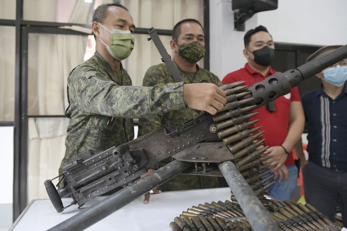 Lieutenant-General Alfredo Rosario, Jr., left, commander of the Western Mindanao Command, inspects a 50 cal. Browning machine gun, part of the 45 firearms seized by army troops from Muslim insurgents aligned with the Islamic State group in Marawi City, southern Philippines on Thursday Mar. 3, 2022. Philippine troops killed at least seven Muslim insurgents aligned with the Islamic State group in a recent offensive in the south and recovered 45 heavy firearms and several bombs and land mines which were to be used for future attacks, military officials said Thursday. (AP Photo/Froilan Gallardo)