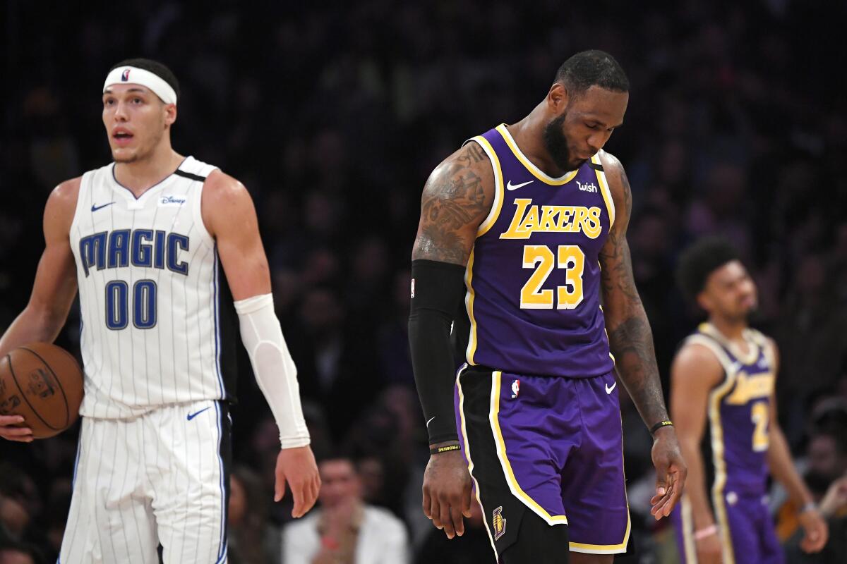 Los Angeles Lakers forward LeBron James, center, walks away along with guard Quinn Cook, right, after missing a 3-point shot in the closing seconds, as Orlando Magic forward Aaron Gordon, left, holds the ball during an NBA basketball game Wednesday, Jan. 15, 2020, in Los Angeles. The Magic won 119-118. (AP Photo/Mark J. Terrill)