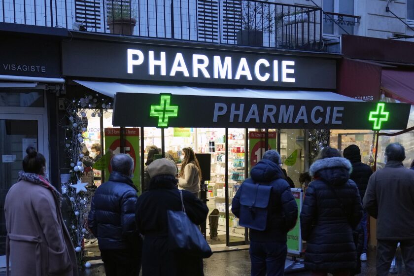FILE - People wait in front of a pharmacy to get a COVID-19 test in Paris, France, Sunday, Jan. 9, 2022. On Friday, Dec. 9, 2022, President Emmanuel Macron announced France will make condoms free in pharmacies for anyone up to age 25 in the new year. (AP Photo/Francois Mori, File)