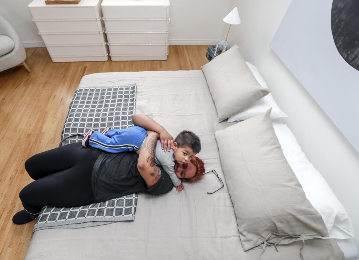 Elana Frey, overwhelmed by emotions, cuddles her 1 1/2-year-old son, Kalani, on her new bed. Frey had been sleeping on the floor, as she couldn't afford any furniture.