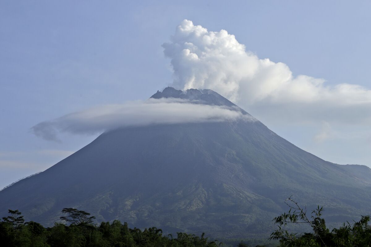 Mount Merapi spews volcanic steam from its crater seen from Sleman, Yogyakarta, Indonesia, Thursday, Jan. 7, 2021. The 2,968-meter (9,737-foot) mountain spewed avalanches of hot clouds on Thursday morning amid its increasing volcanic activities. (AP Photo/Taufiq Rozzaq)