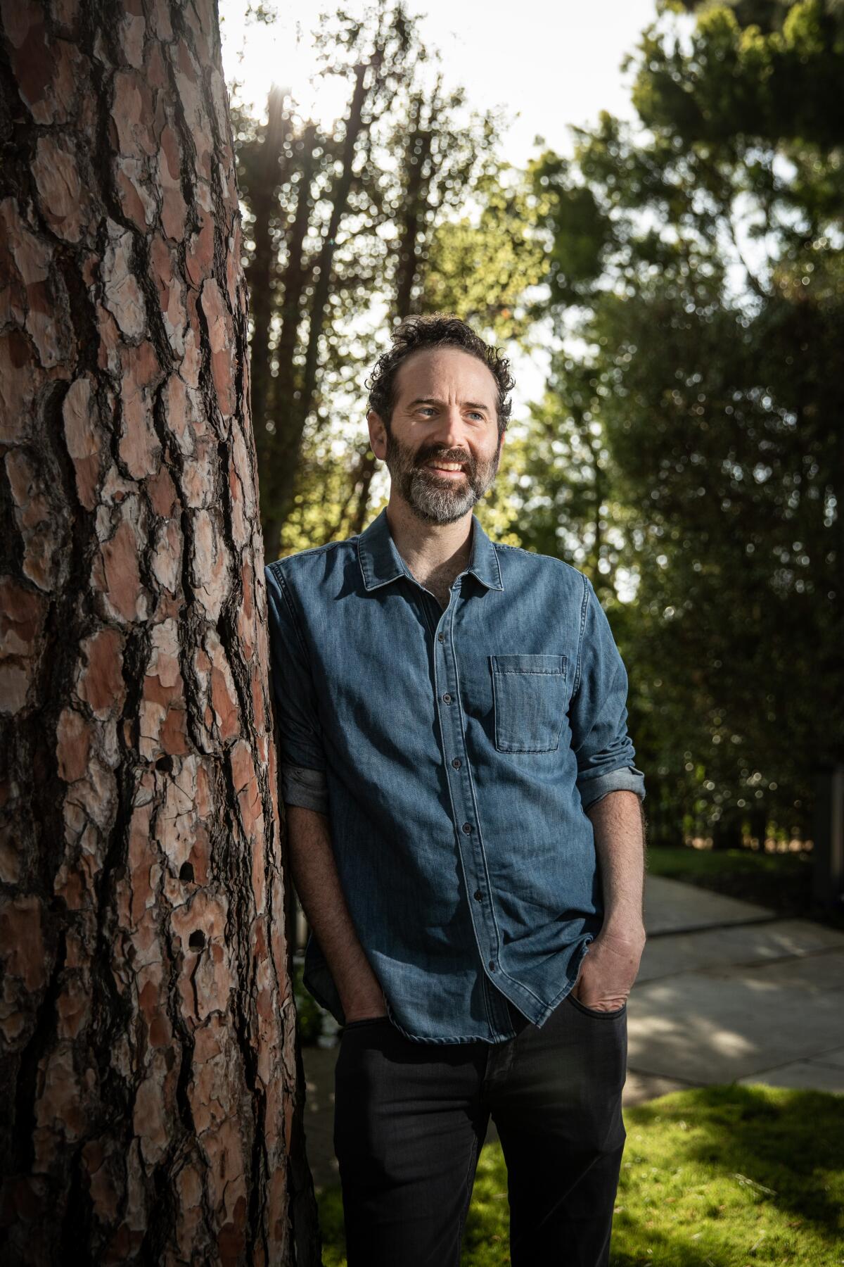 Author and playwright Dan O'Brien leaning against a tree. 