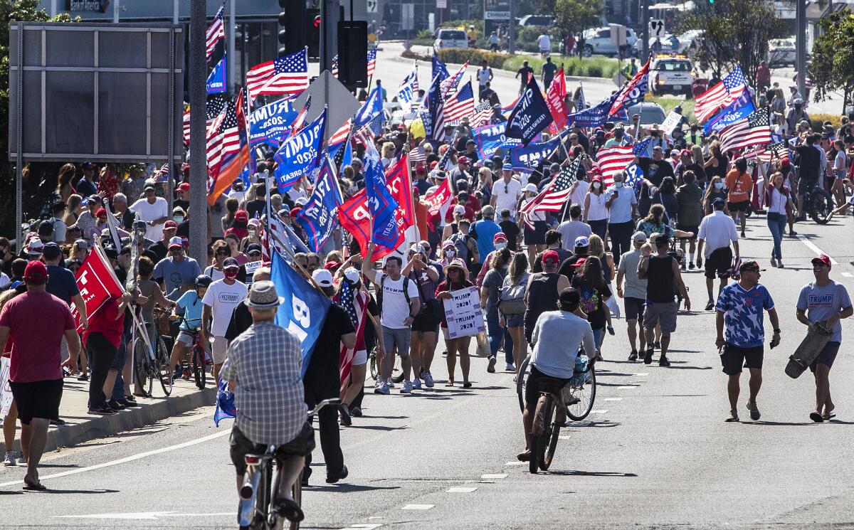 Trump supporters wave flags and signs while hoping to get a glimpse of the president's motorcade on Sunday in Newport Beach.