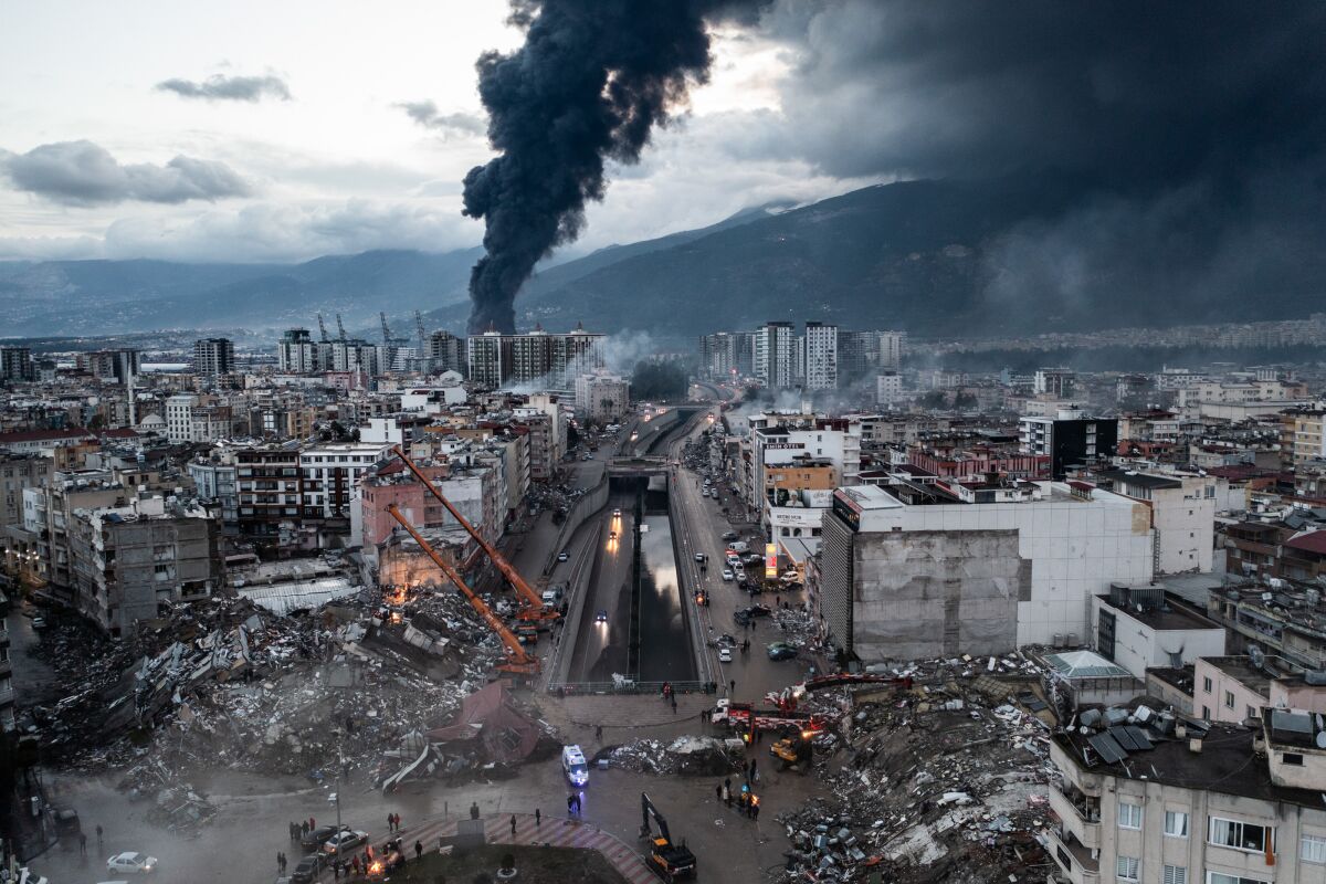 Smoke billows above the rubble from an earthquake