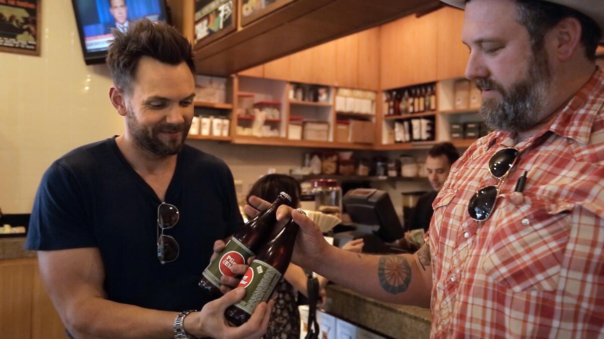 Joel McHale, left, gets bottles of Pliny the Elder handed to him from Jeremy Fraye, the general manager at The Oaks Gourmet Market. McHale, a beer fan, enjoys the hoppy flavor of Pliny and will search the city for it.