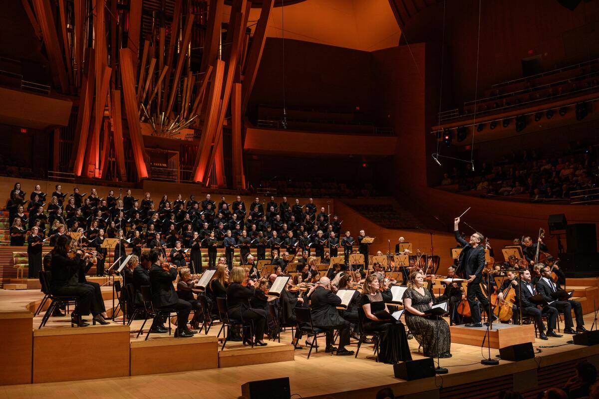 An orchestra and chorale group performing in a concert hall. 