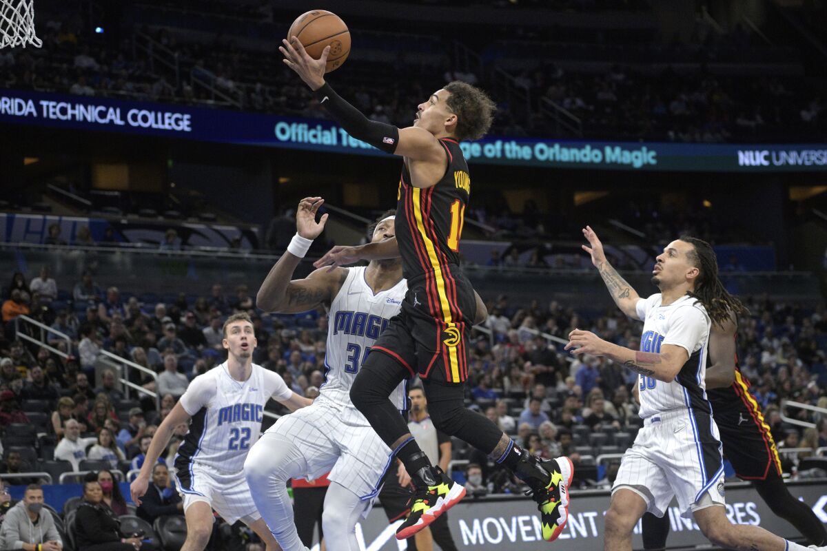 Atlanta Hawks guard Trae Young (11) goes up for a shot in front of Orlando Magic forward Franz Wagner (22), center Wendell Carter Jr. (34) and guard Cole Anthony (50) during the first half of an NBA basketball game, Wednesday, Feb. 16, 2022, in Orlando, Fla. (AP Photo/Phelan M. Ebenhack)
