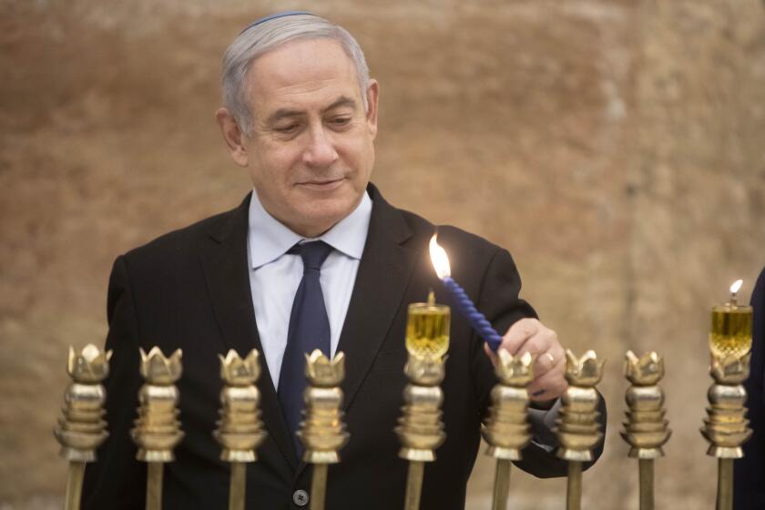 Israeli Prime Minister Benjamin Netanyahu, lights a Hanukkah candle at the Western Wall, the holiest site where Jews can pray in Jerusalem's old city, Sunday, Dec. 22, 2019. (AP Photo/Sebastian Scheiner)