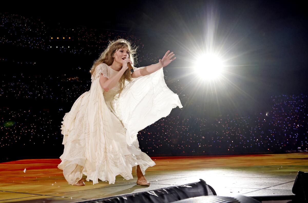 Taylor Swift performing in a white dress on stage