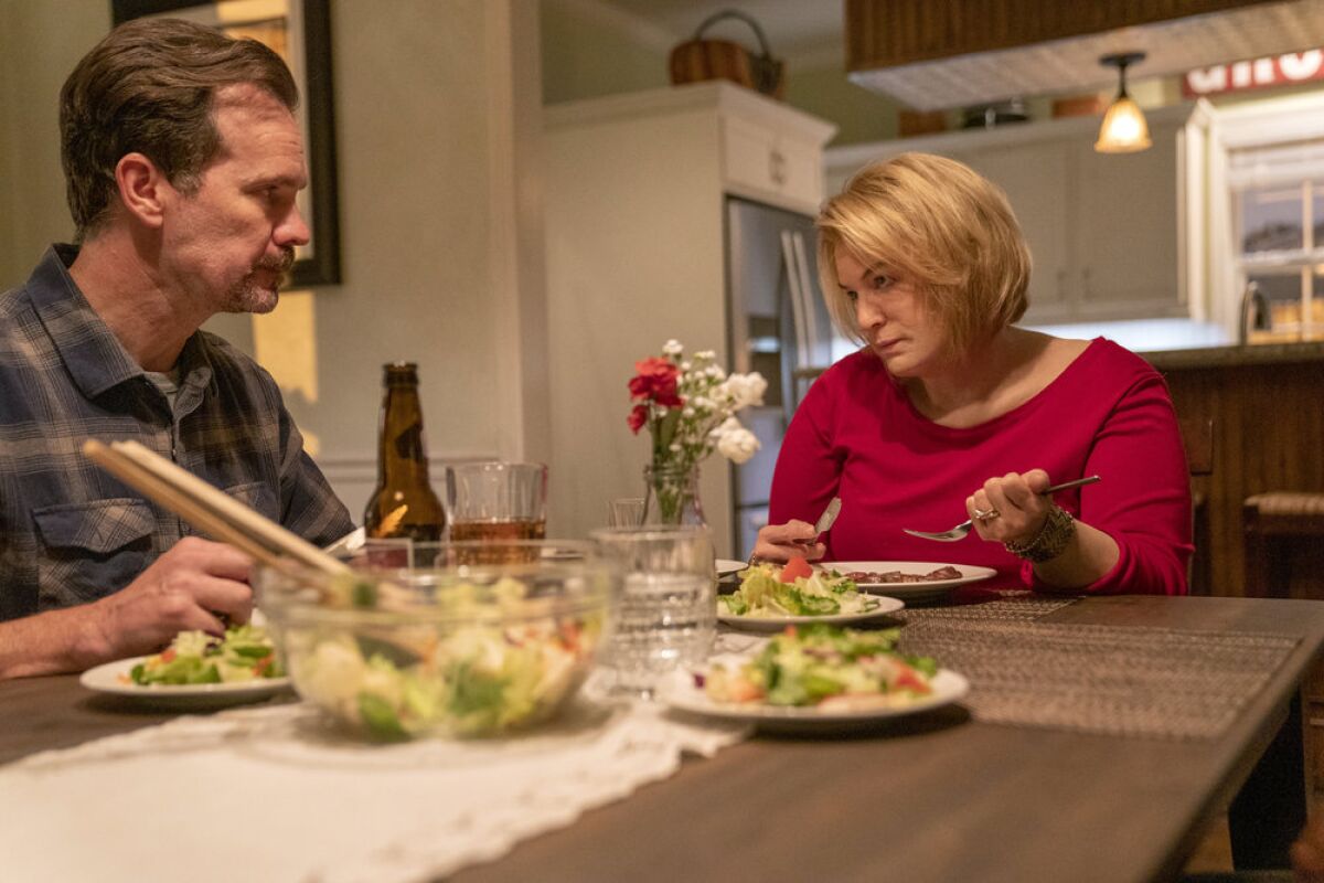 A man and women eat salad at a dinner table