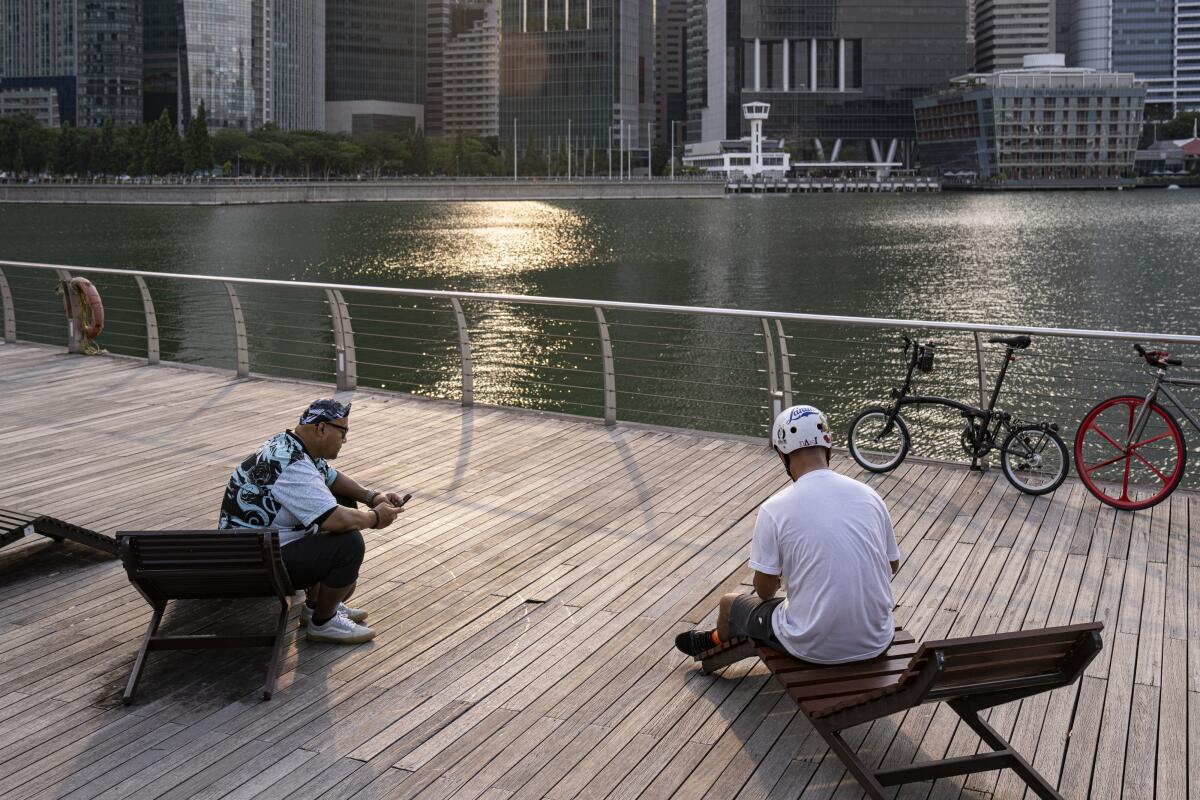 Observing new government guidelines, people sit at a distance from each other at Singapore's Marina Bay on Monday.