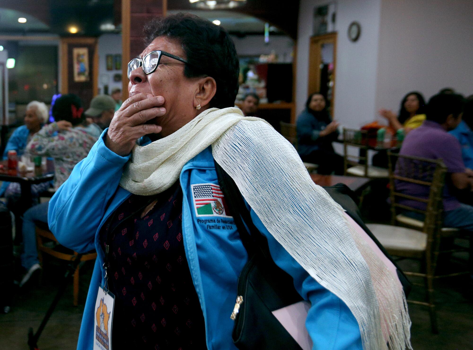Filled with emotions, 63-year-old Lucia Rodriguez Adrian, hand over her mouth, walks to meet her children