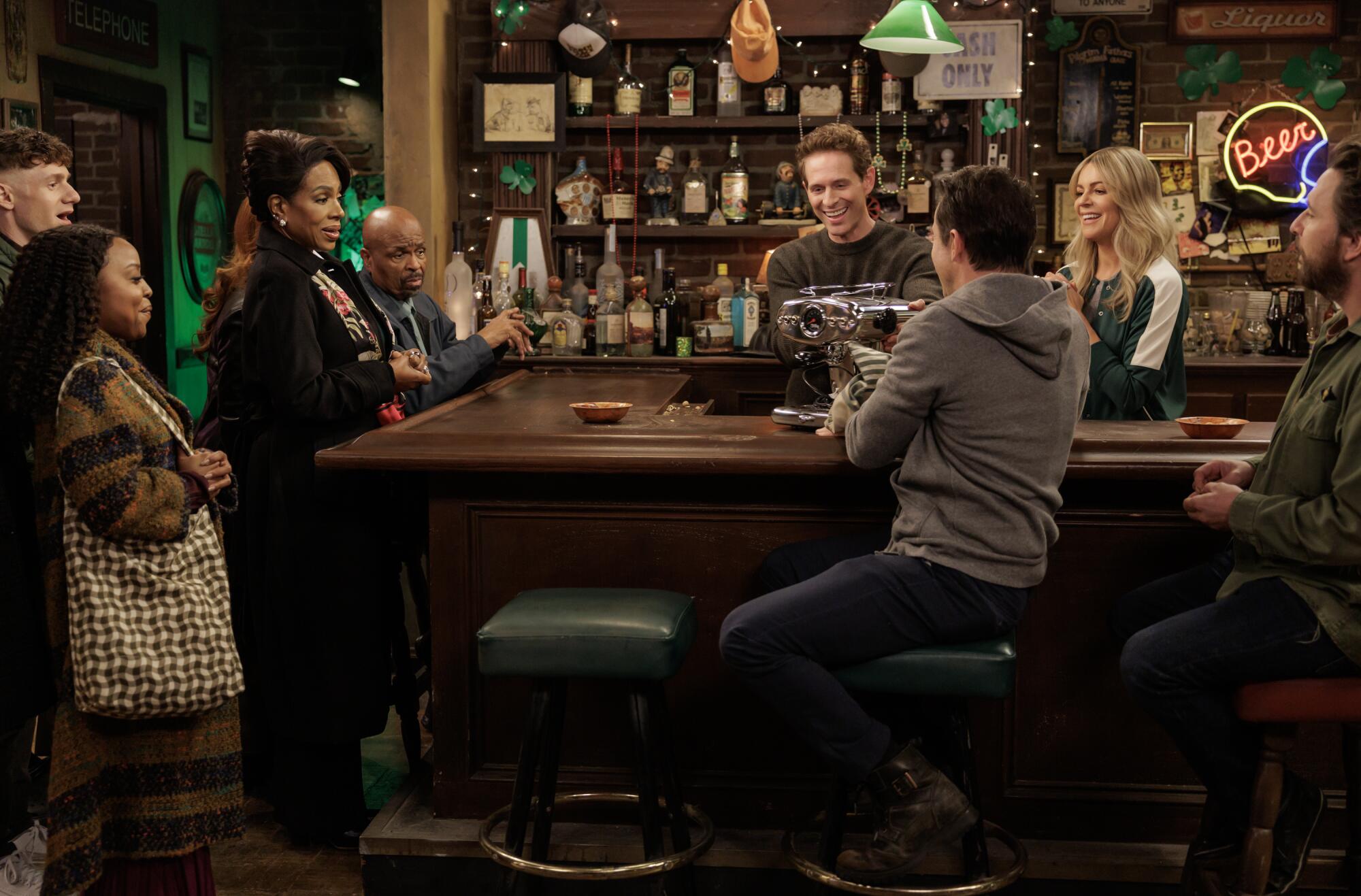 A group of people standing around a bar looking a piece of machinery.